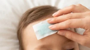Xô Febre — adesivo de gel refrescante sendo aplicado na testa de bebê (imagem gerada por IA)
